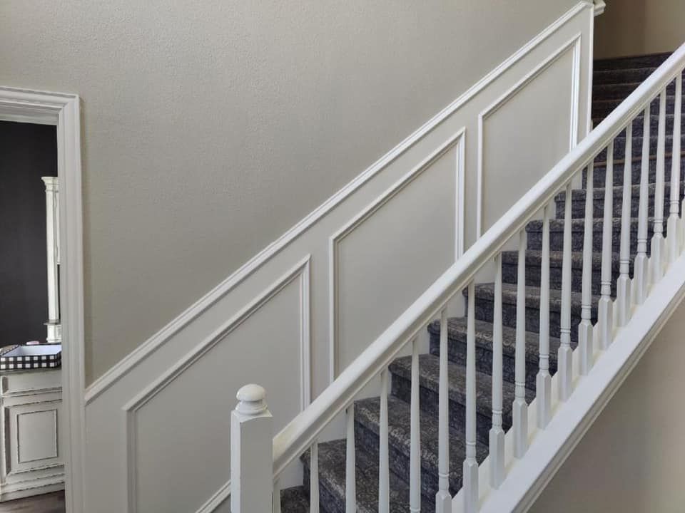 Staircase with white trim and railing, gray carpeted stairs, and paneling on the wall.
