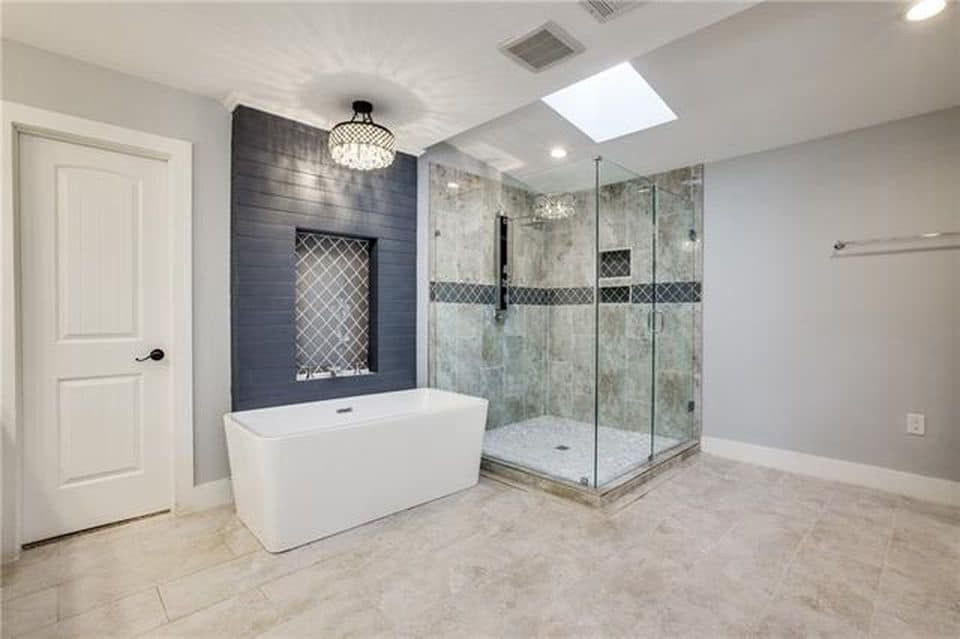 Modern bathroom with tub, glass shower, gray walls, and a skylight.