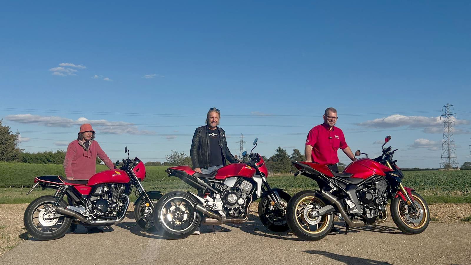 Three men with red motorcycles parked outdoors.