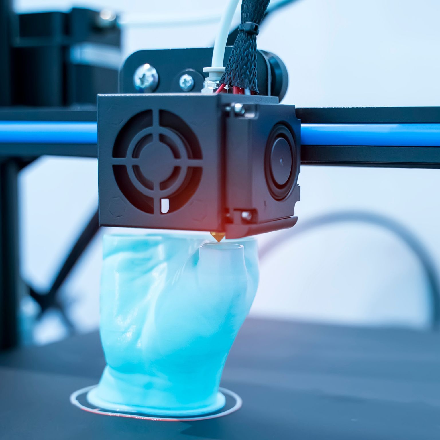 A close up of a 3d printer printing a glove