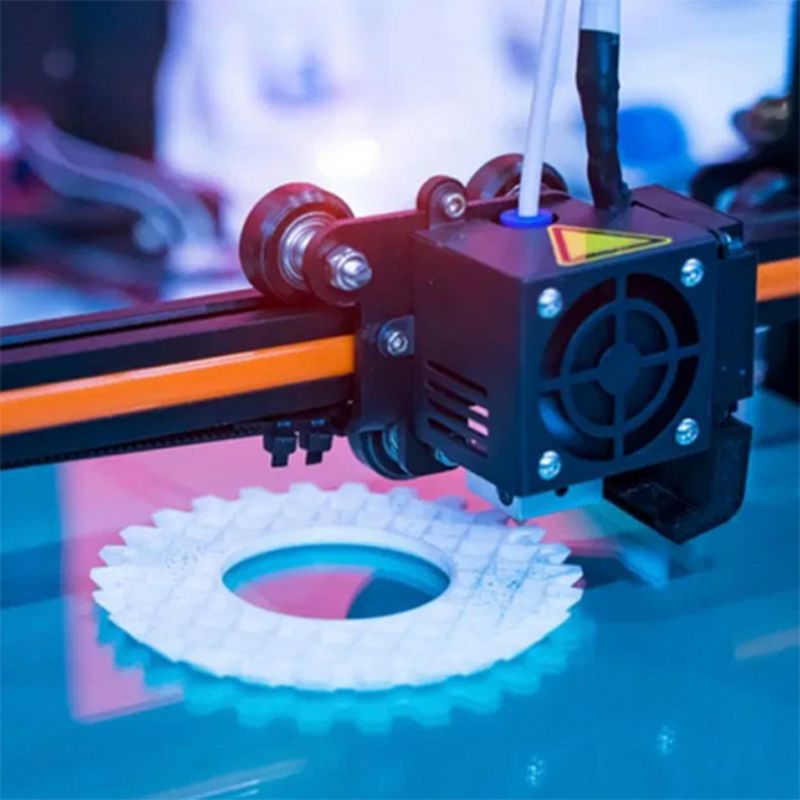A close up of a 3d printer printing a gear