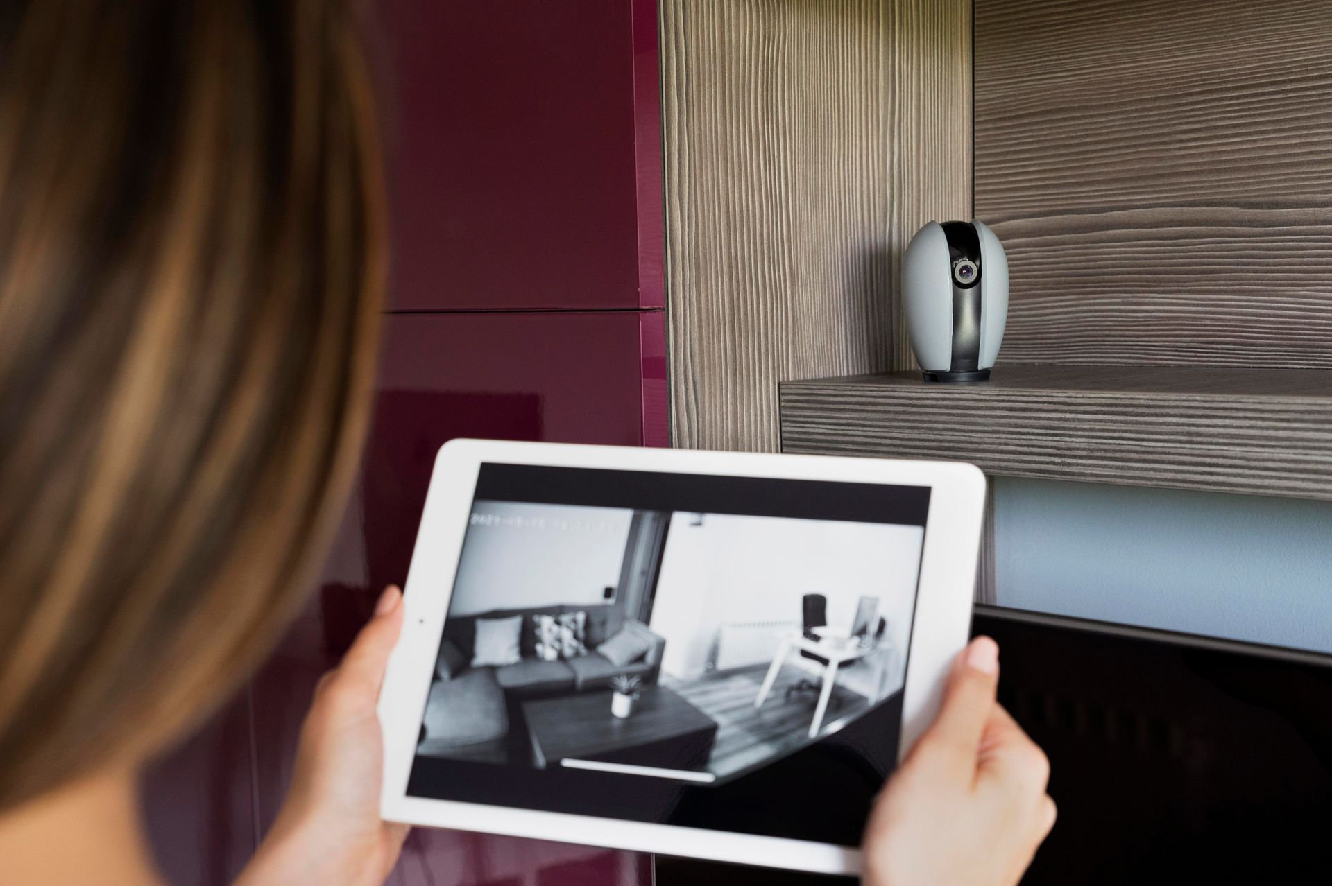 Une personne tenant une tablette affichant une scène de salon en noir et blanc dans un intérieur moderne