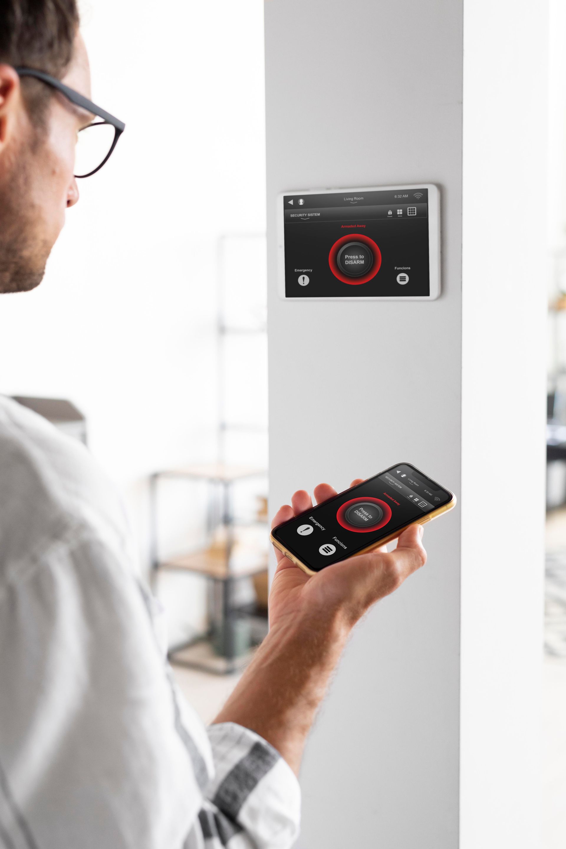 Une personne utilise un smartphone pour contrôler un thermostat mural dans une pièce lumineuse.