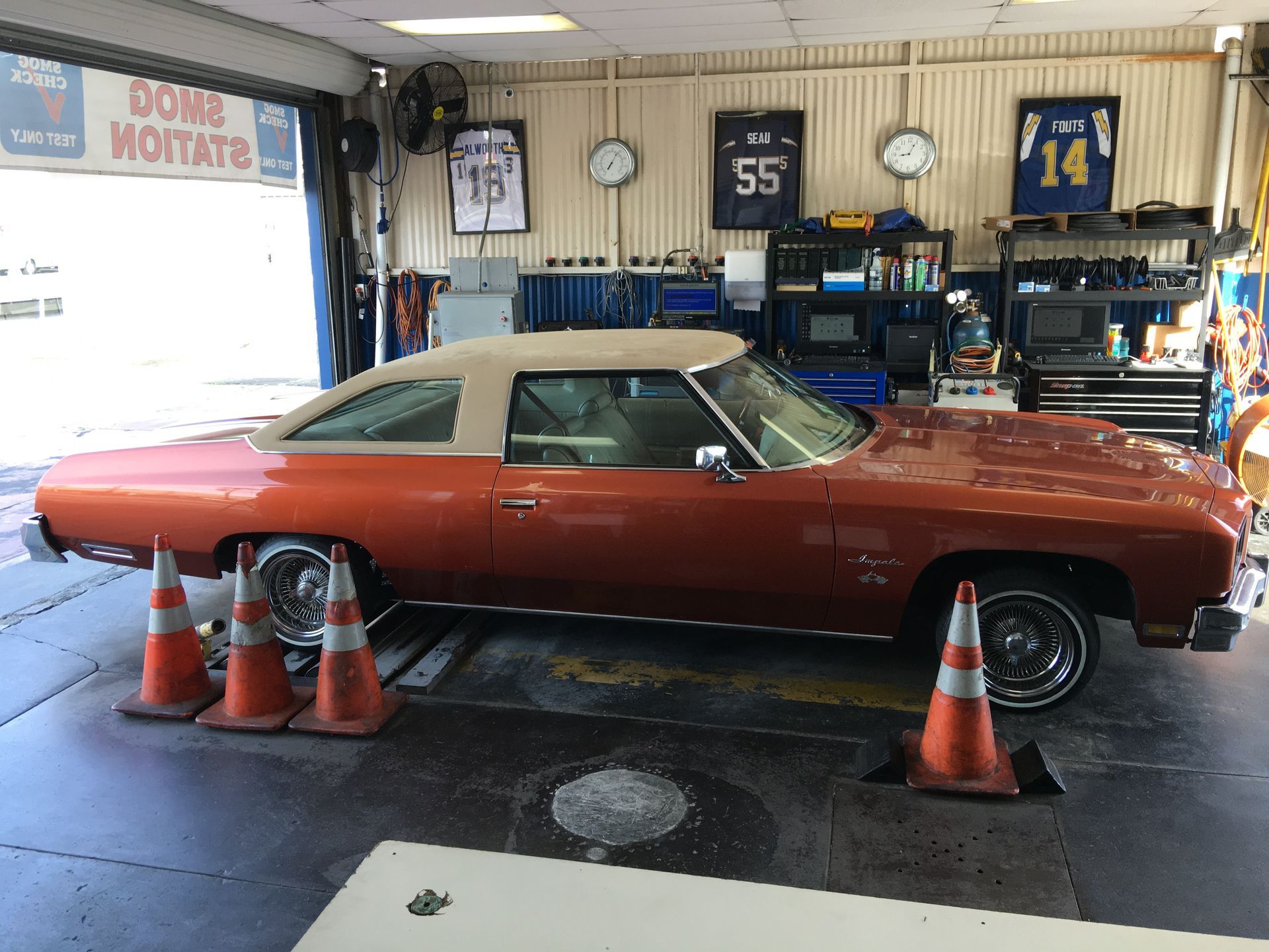 Orange classic convertible parked inside a car showroom with orange cones nearby