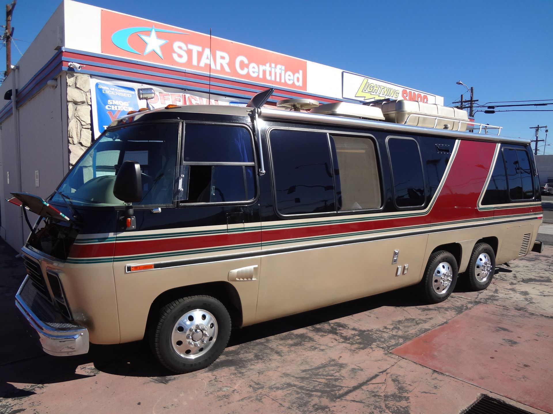 Tan-and-black RV with red stripe parked outside a STAR Certified service station