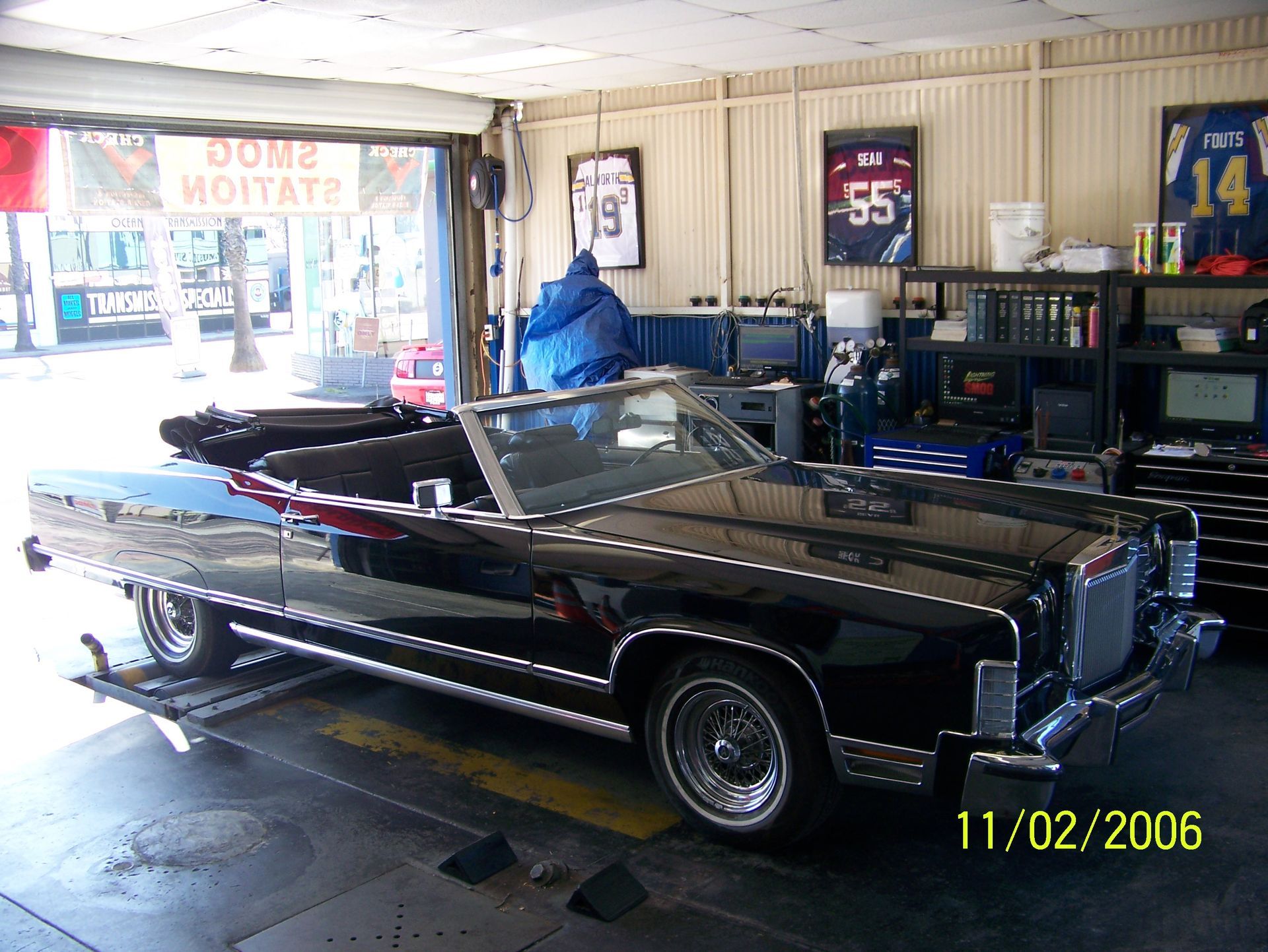 Black vintage convertible in a garage, with framed sports jerseys on the wall.