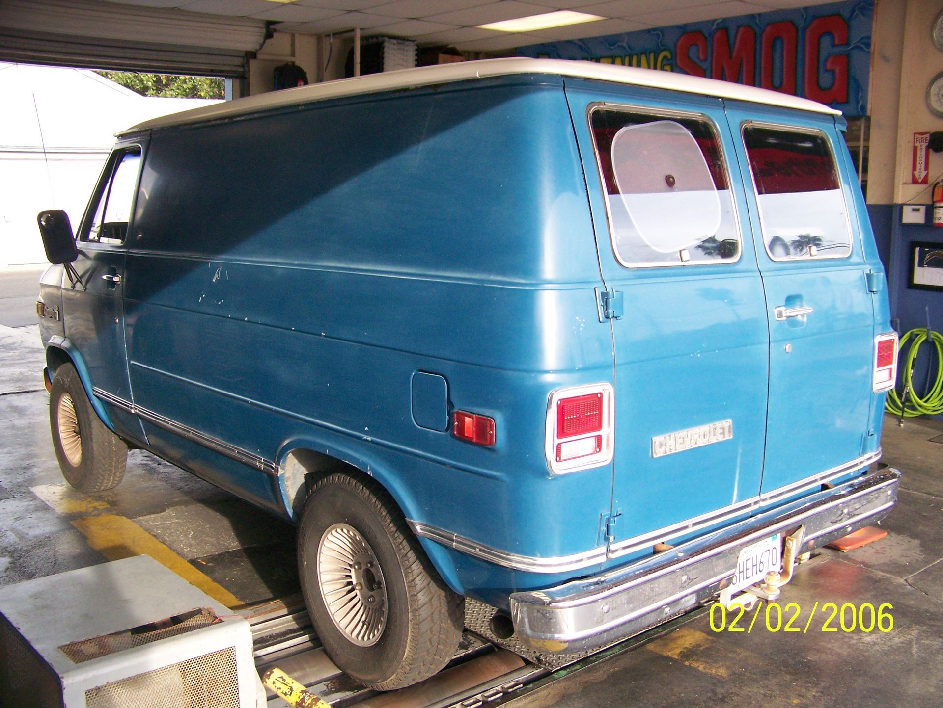 Blue cargo van parked indoors, rear three-quarter view, with a date stamp in the corner.