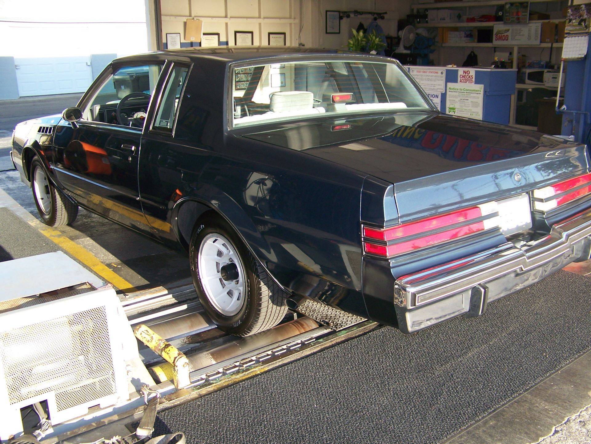 Black sedan on a car conveyor inside a garage or workshop