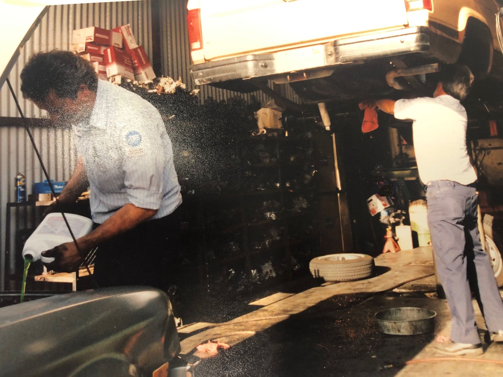 Two workers washing a truck at a nighttime car wash with soap and water spraying everywhere