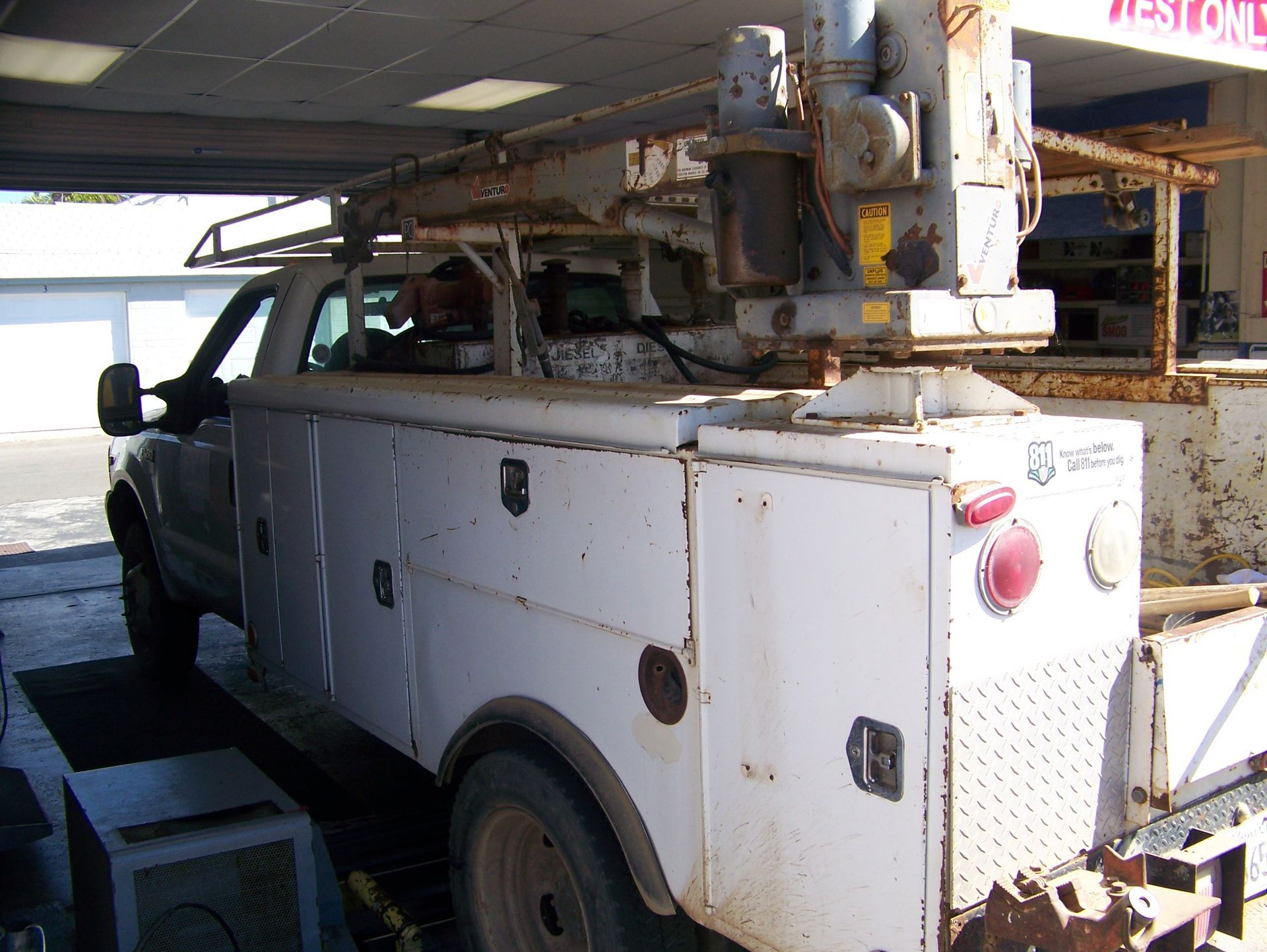 White utility truck with a bucket lift parked in a garage or workshop