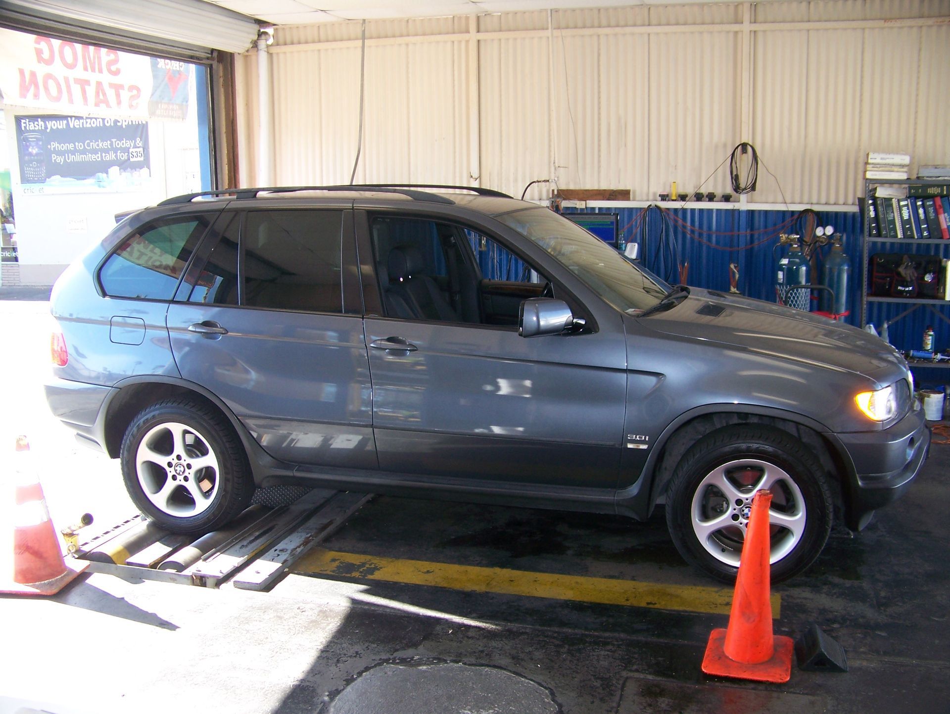 Gray SUV on a dynamometer in a garage, surrounded by orange cones and equipment.