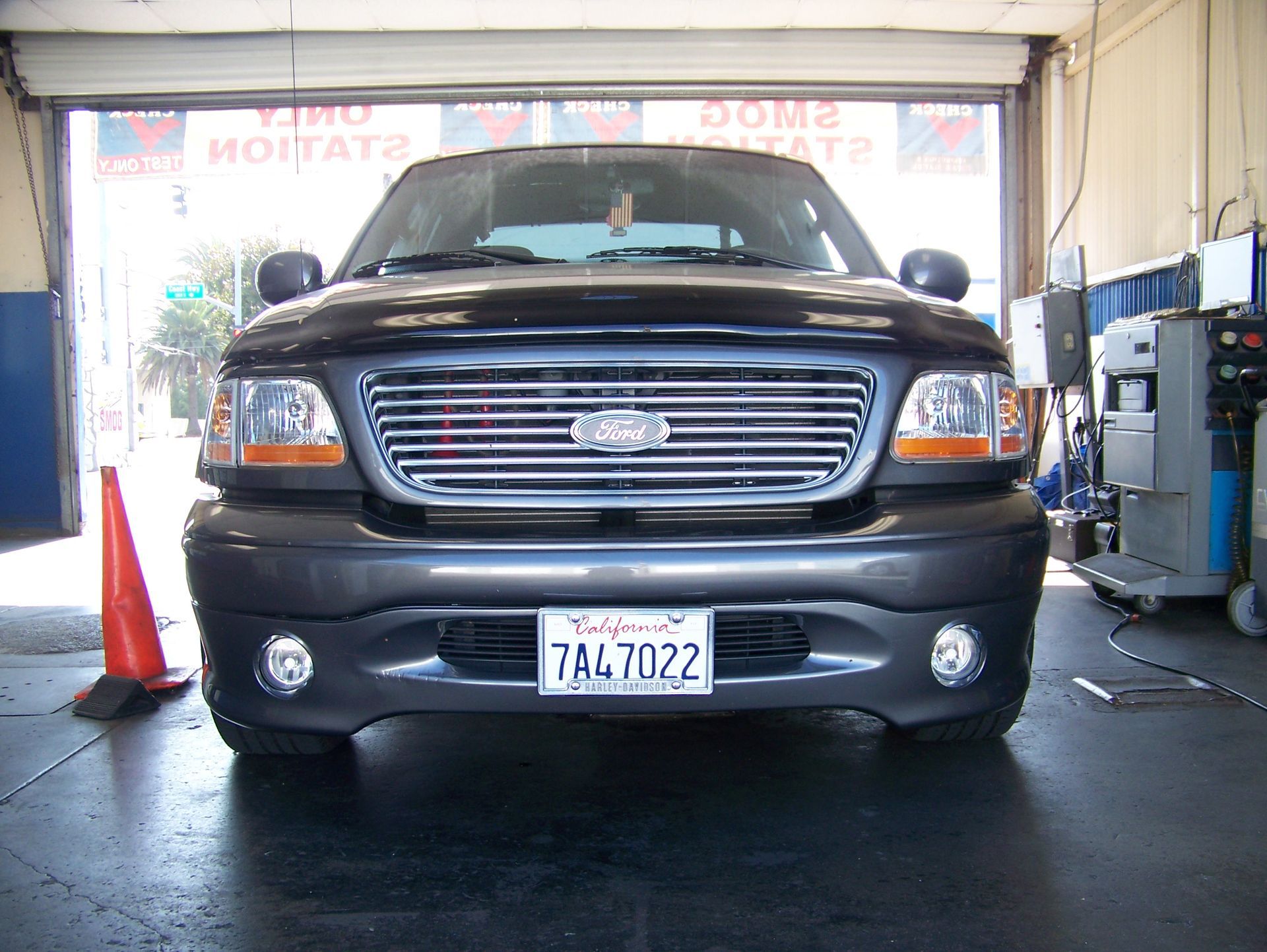 Black pickup truck in an auto shop bay, front view with a California license plate.
