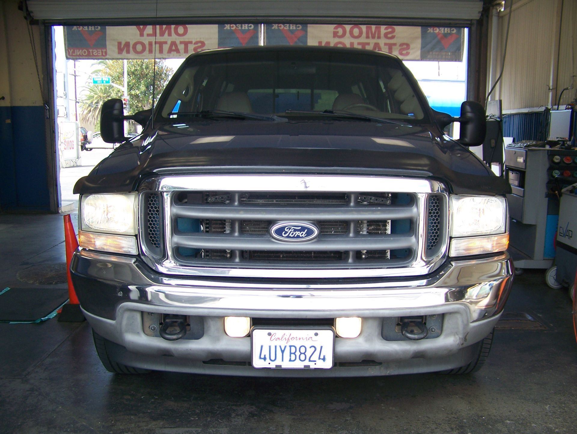 Blue Ford pickup truck parked inside an auto shop, front view with chrome grille and license plate