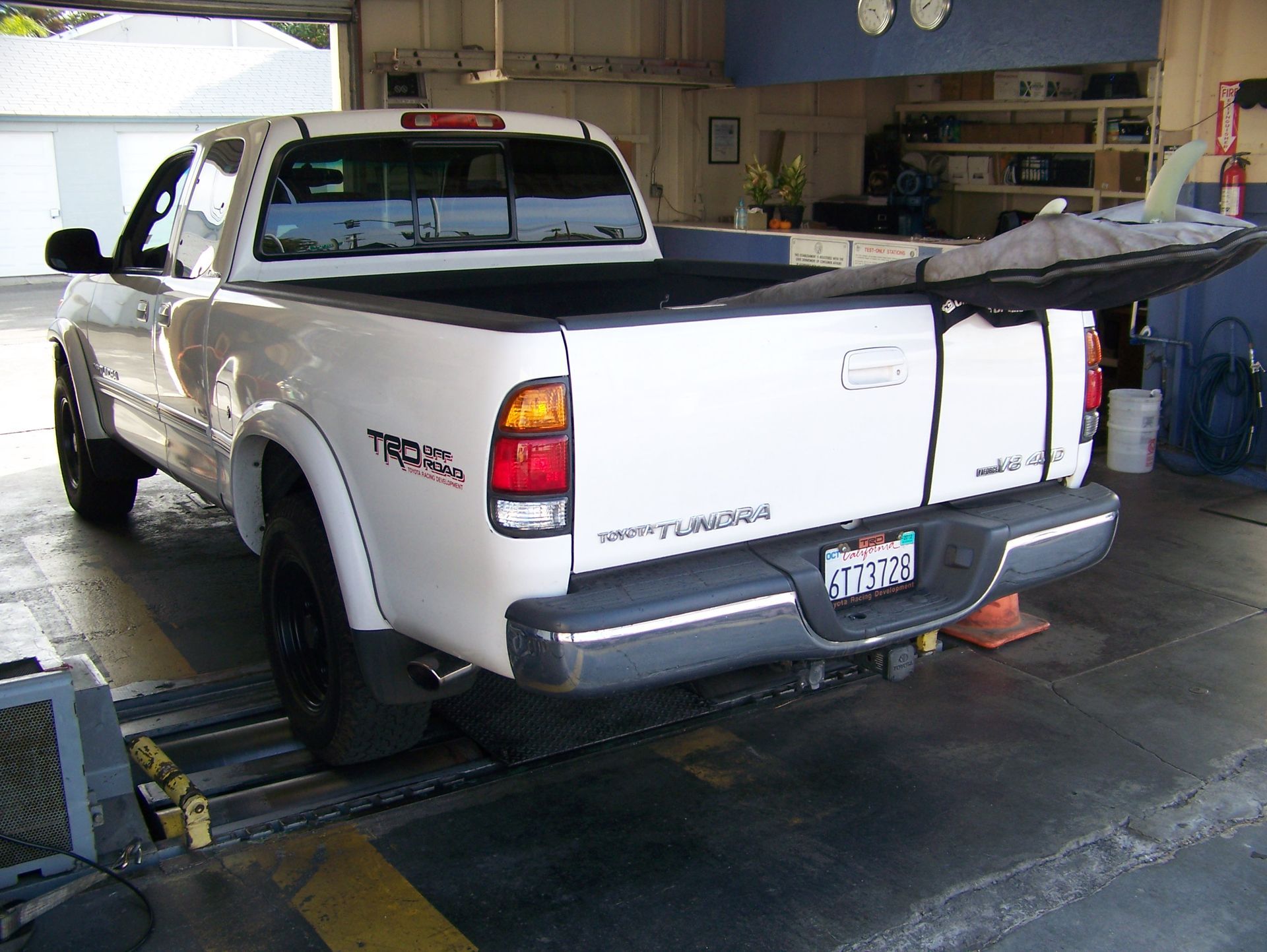 White pickup truck with open tailgate parked inside a garage, rear view.