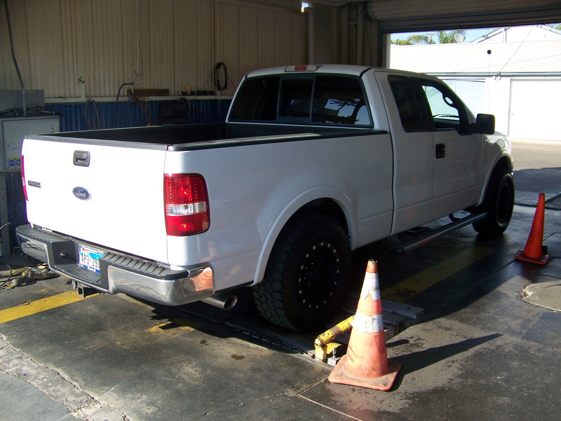 White pickup truck in a garage, parked near traffic cones and a wet floor