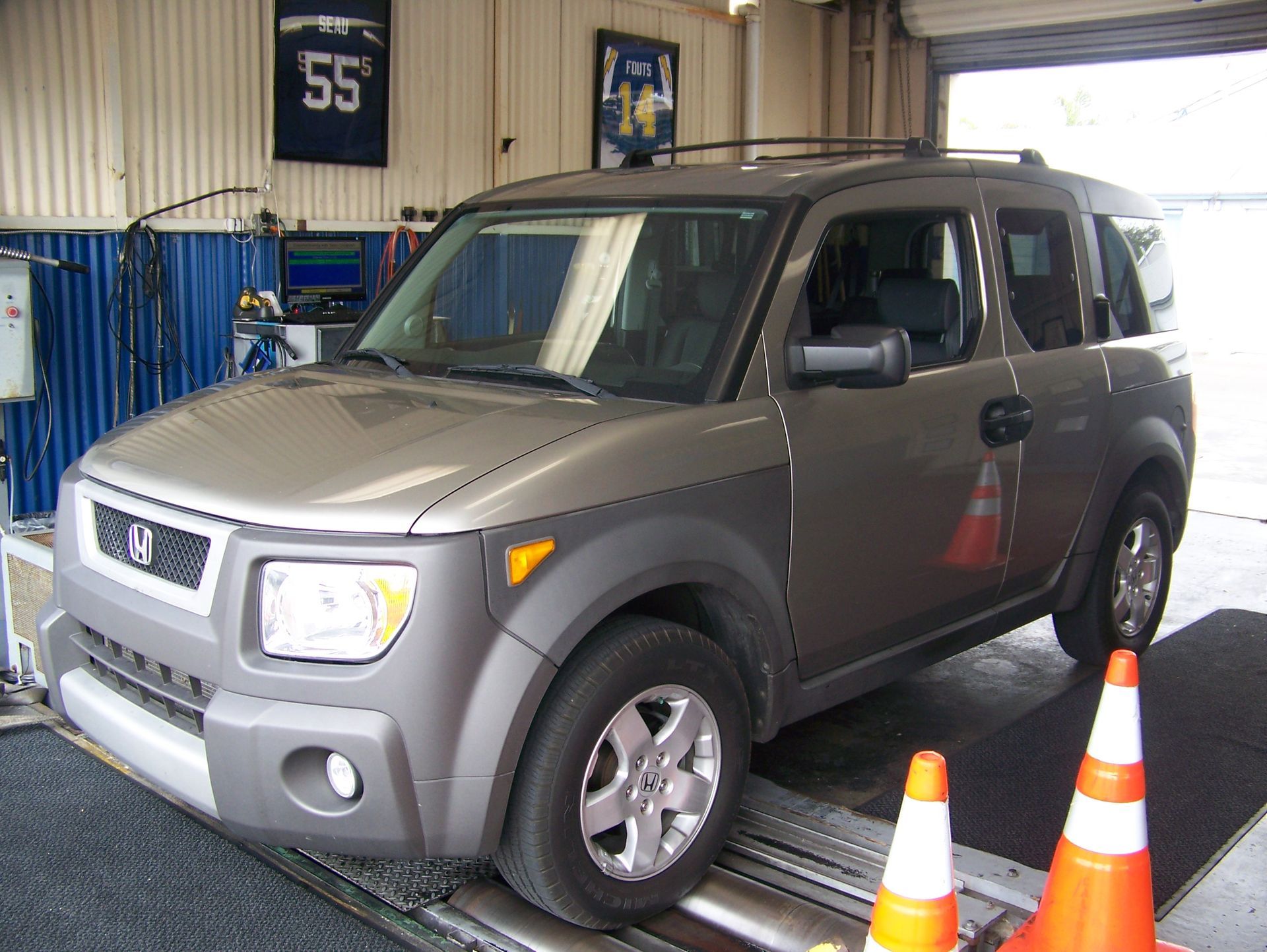 Gray Honda SUV in a garage service bay beside orange traffic cones and a blue lift.