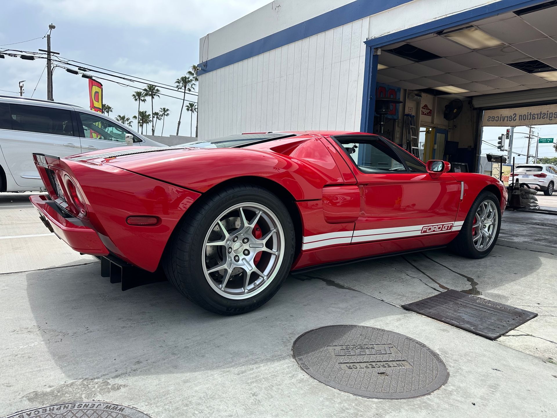 Red sports car parked outside a garage, viewed from the side.