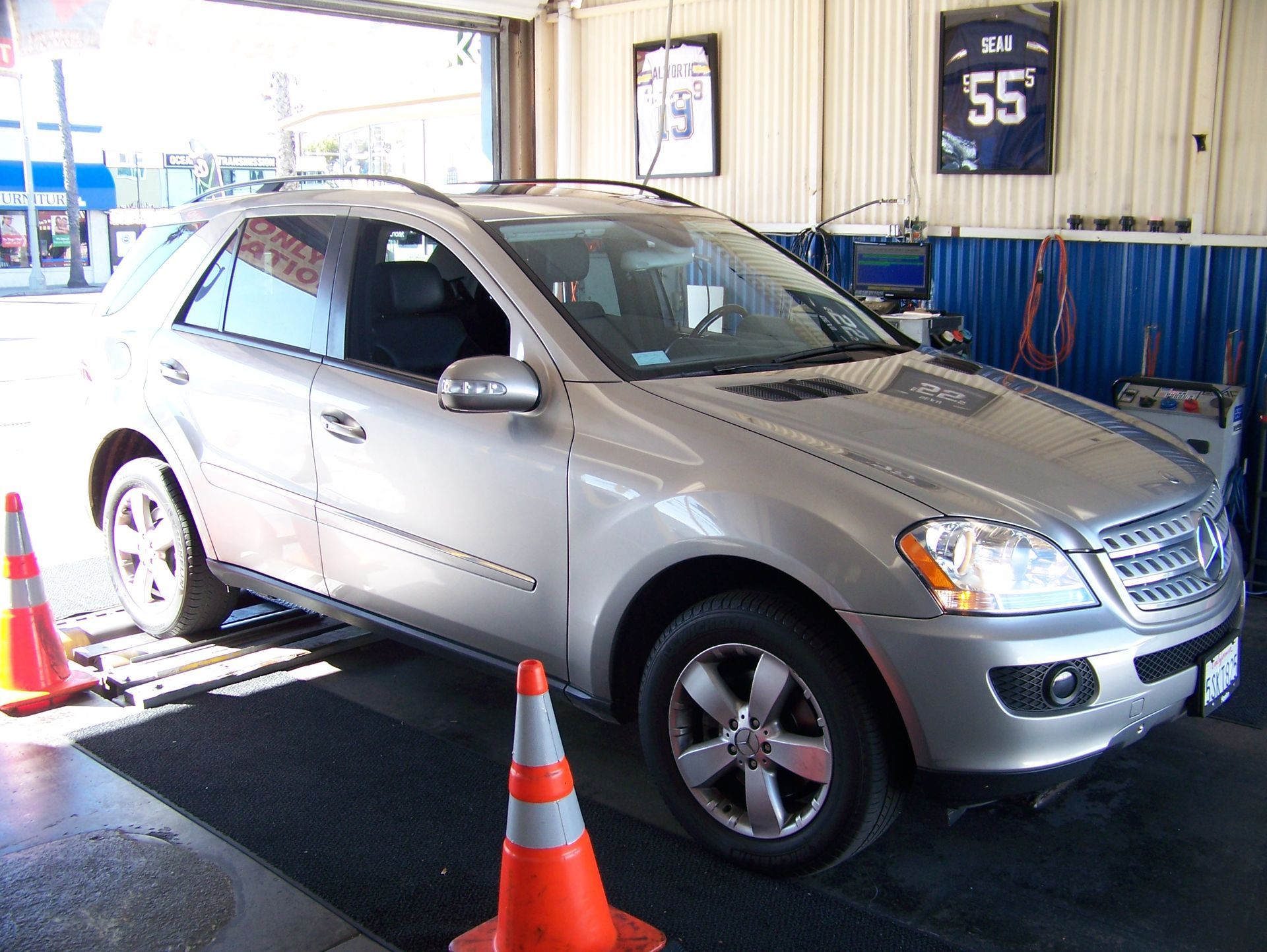 Silver SUV on a garage alignment lift, surrounded by orange cones in a service bay