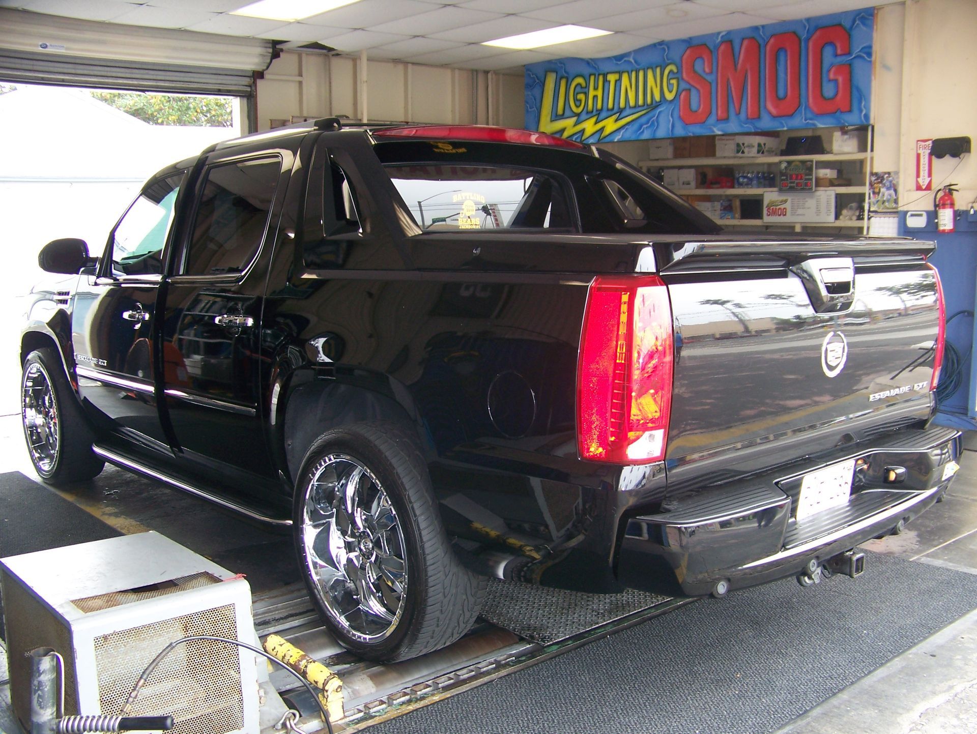 Black pickup truck on a dynamometer in a smog inspection station