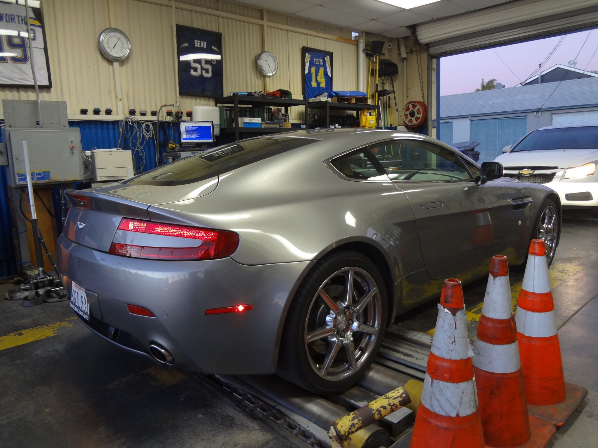 Silver sports car in a garage on a dynamometer, with orange cones in the foreground
