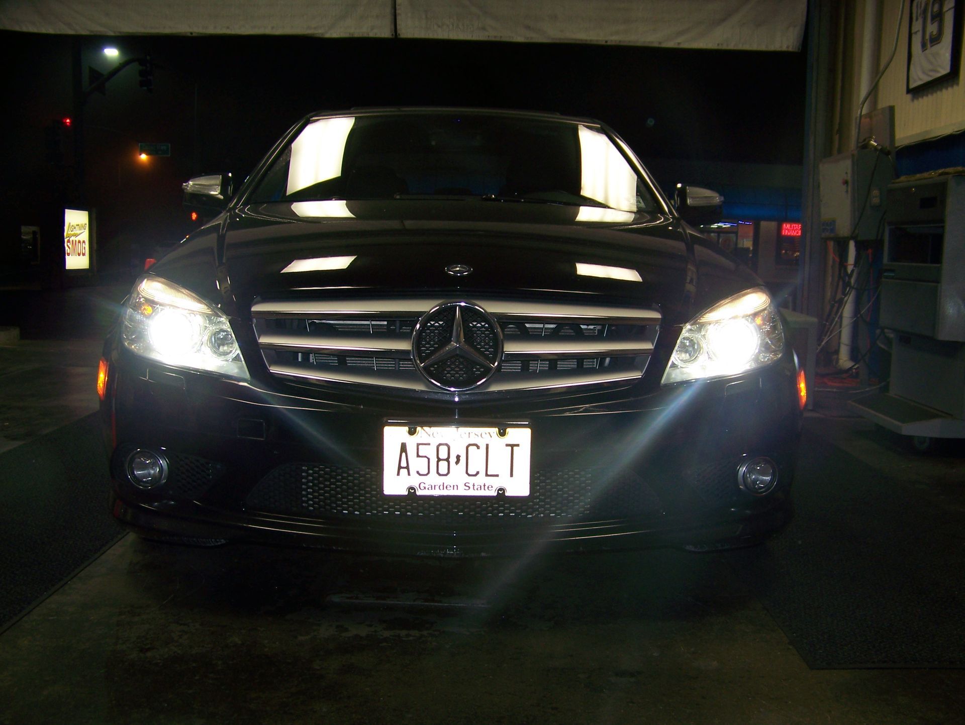 Front view of a black Mercedes SUV with headlights on in a dark garage