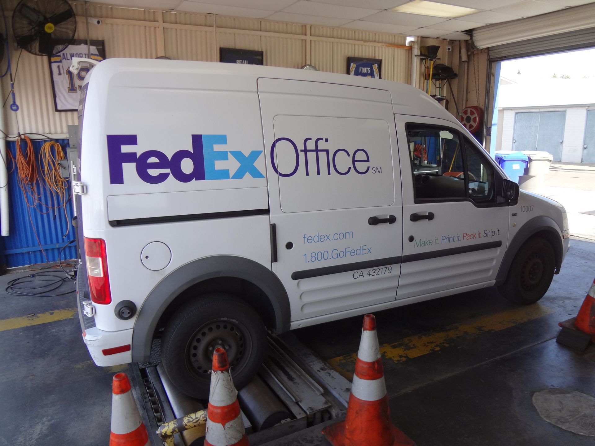 FedEx Office delivery van in a garage bay, surrounded by orange cones