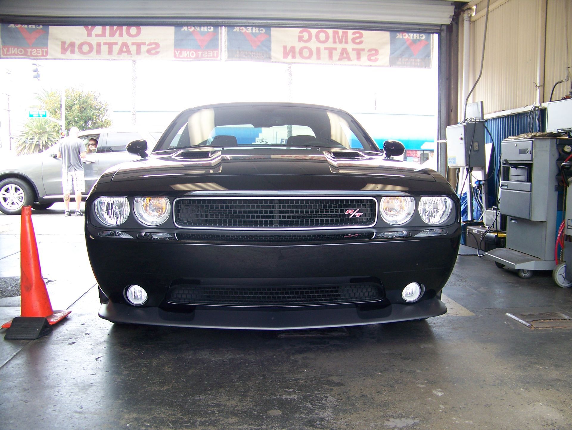 Front view of a black Dodge Charger in a garage, with cones and shop equipment nearby