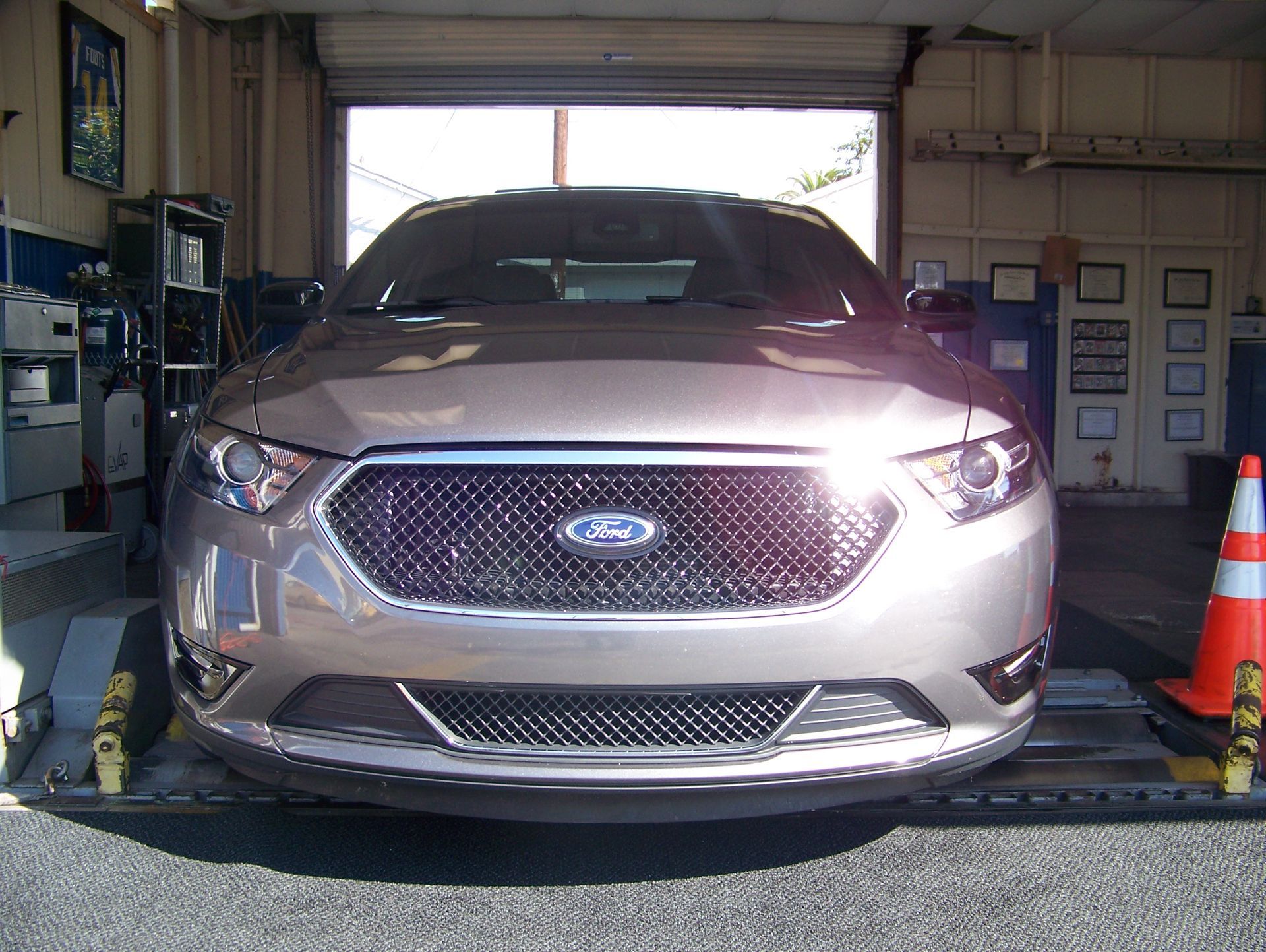 Silver Ford SUV parked inside a garage, front view with orange cones on either side.
