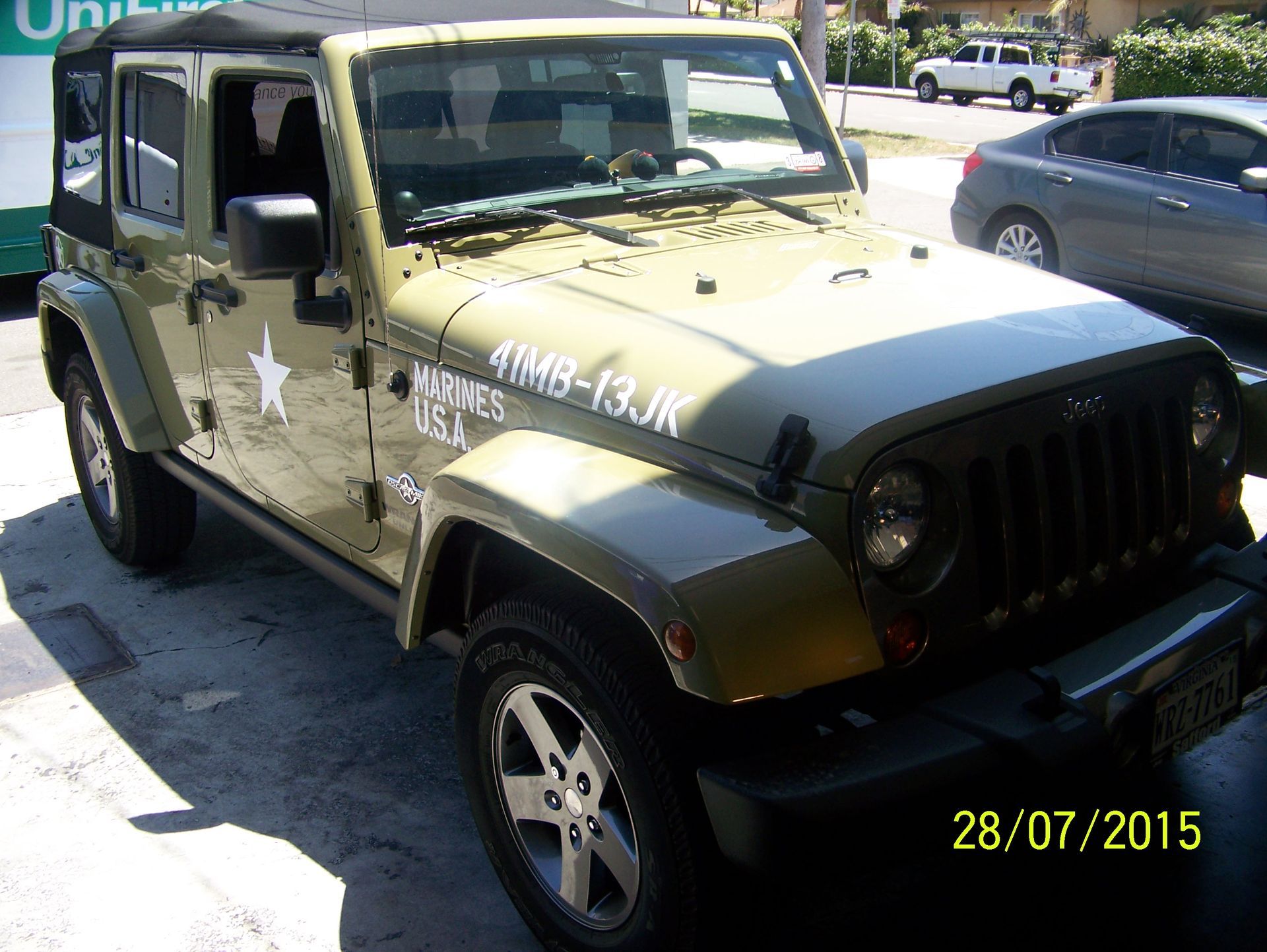 Camouflaged Jeep parked on a sunny street, with white military-style star markings.