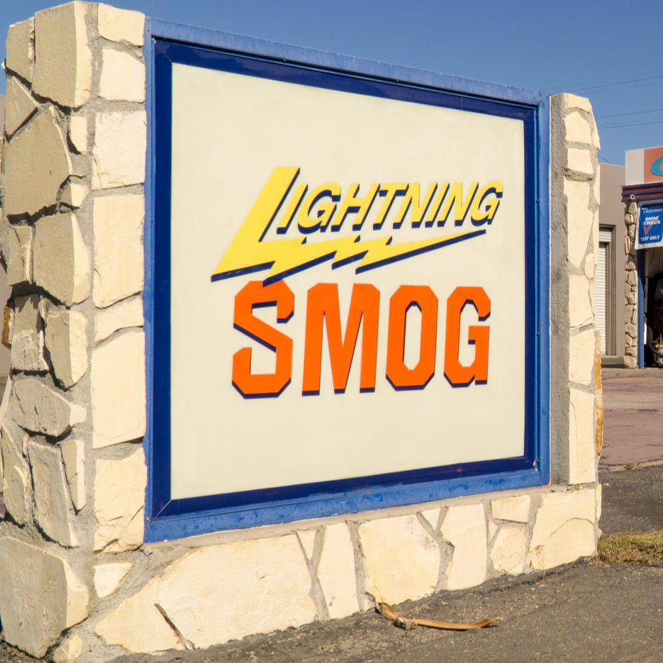 Outdoor sign for Lightning Smog in blue and orange on a stone wall