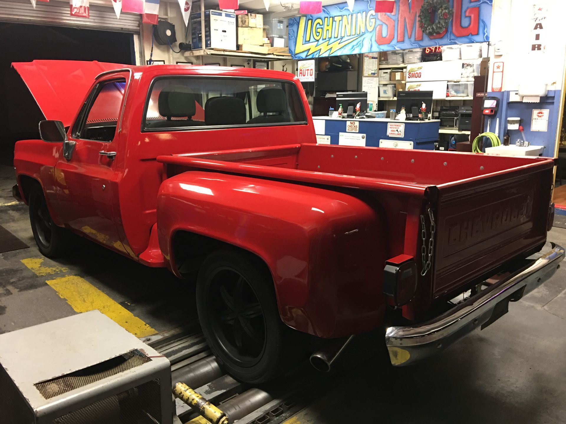 Red custom classic pickup truck in a garage, hood open and rear bed exposed
