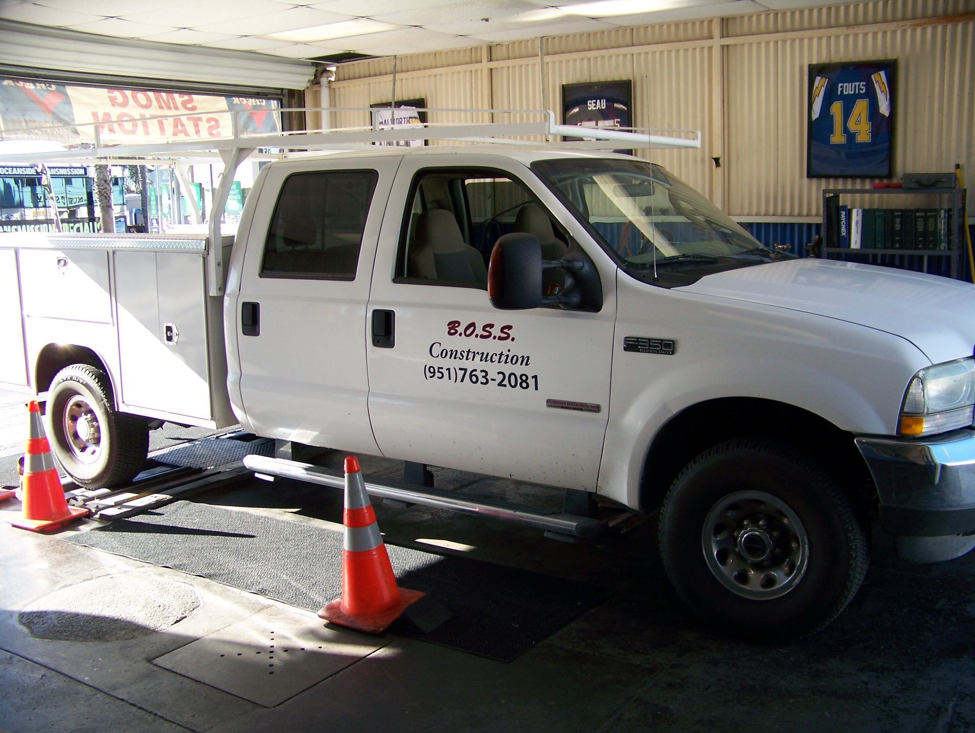 White pickup truck parked indoors with orange traffic cones, seen in a garage or showroom.