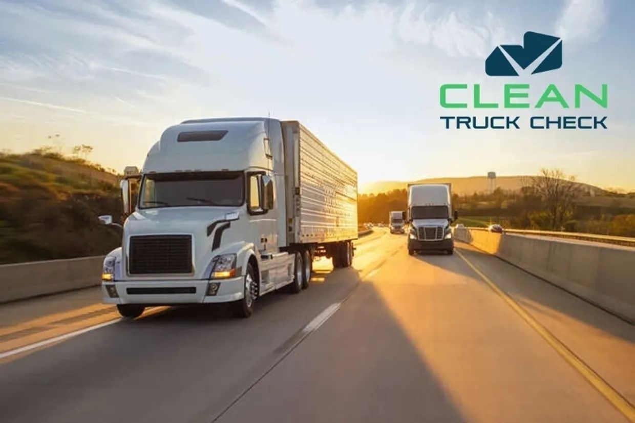 Two white semi-trucks driving on a highway at sunset with a Clean Truck Check logo