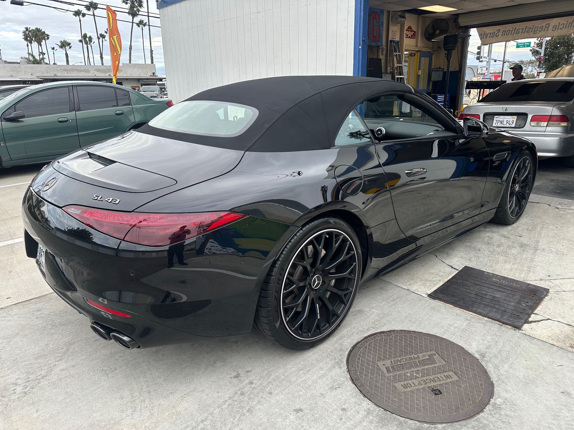 Black convertible sports car parked outside a garage, rear three-quarter view