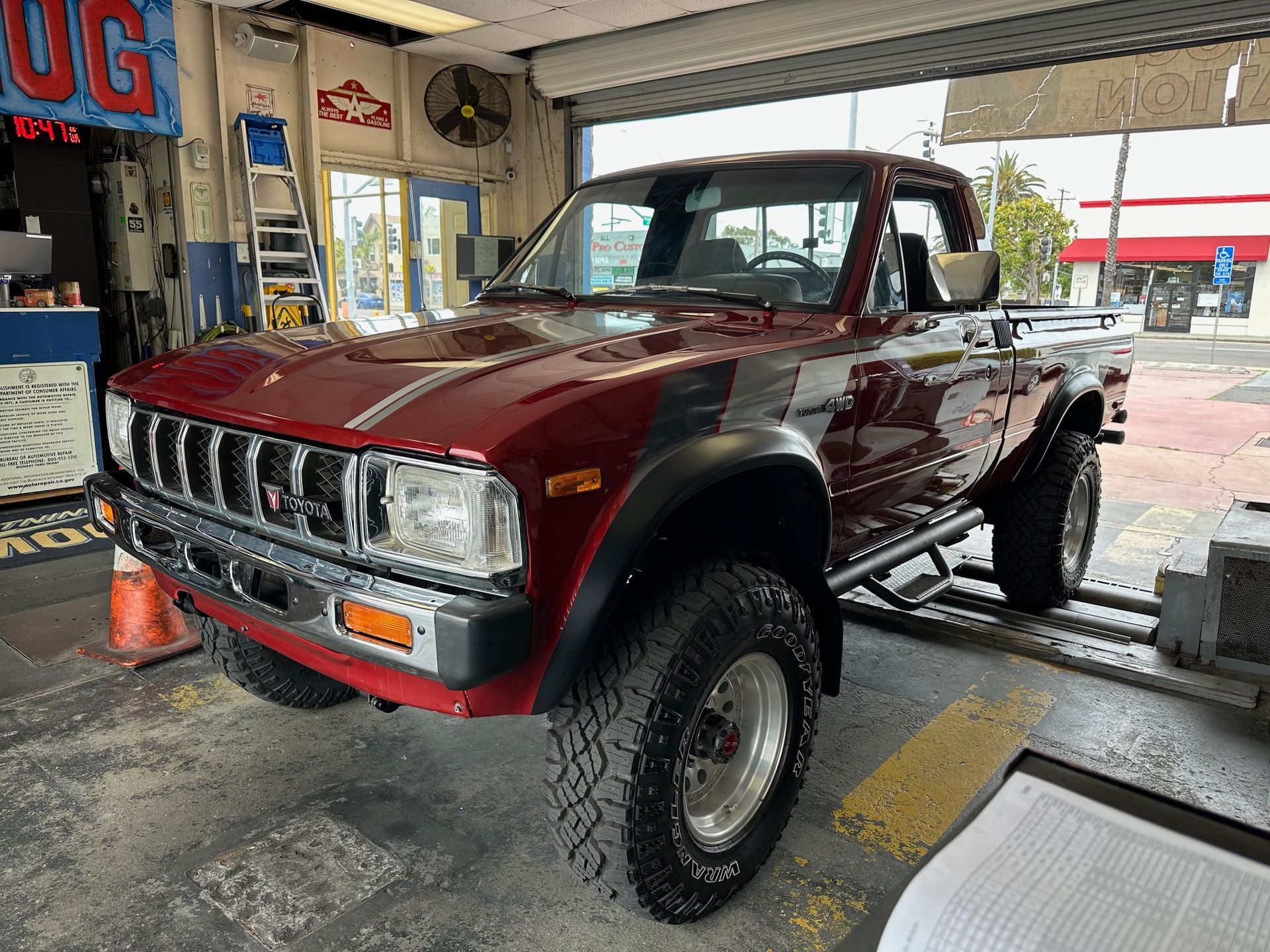 Maroon pickup truck lifted on a garage lift, shown in a repair shop.