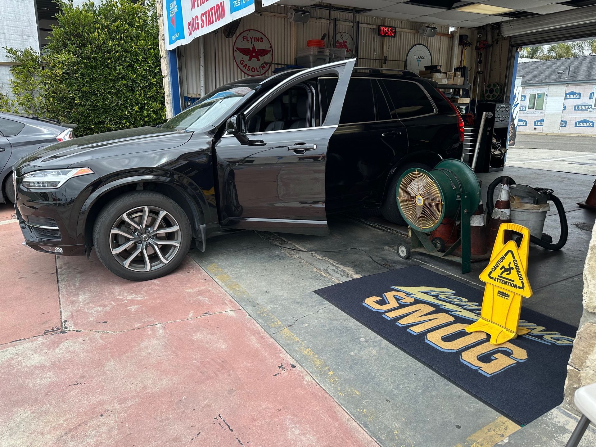 Black SUV parked at a car wash with the driver door open and a caution sign nearby