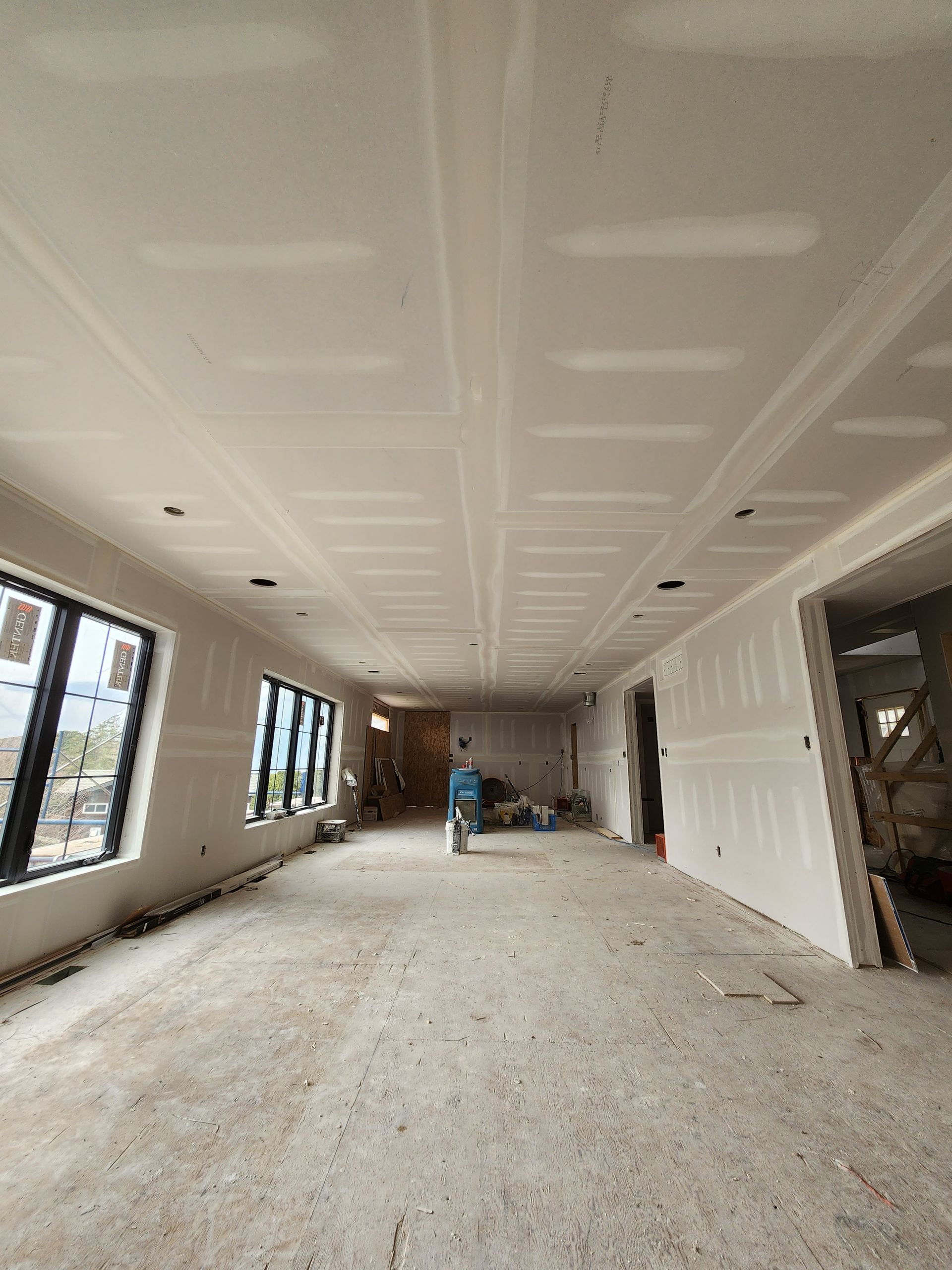 a large room with a lot of windows and drywall on the ceiling .