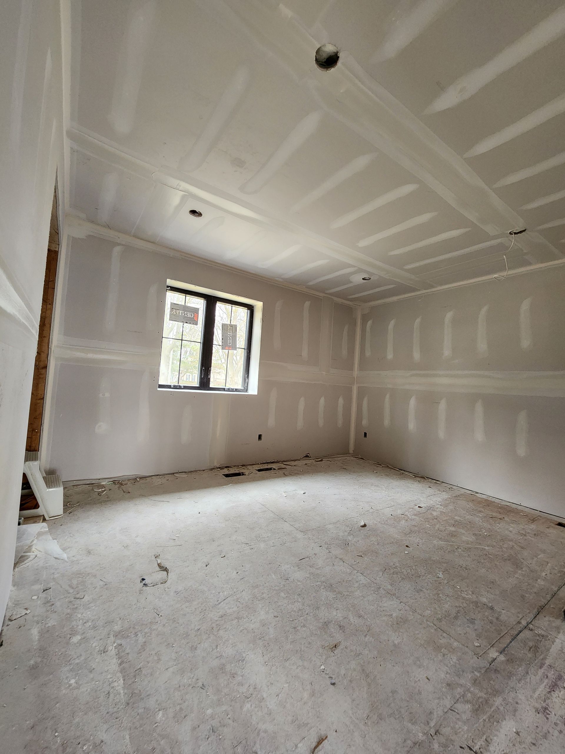 an empty room with drywall and a window