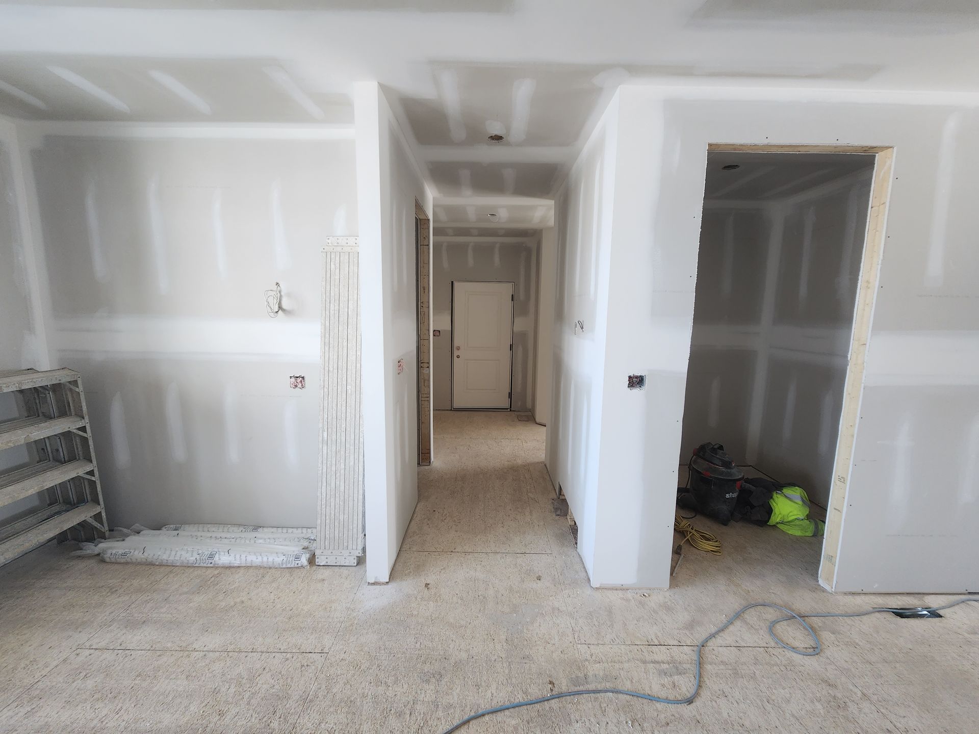 a hallway in a house under construction with drywall on the walls .
