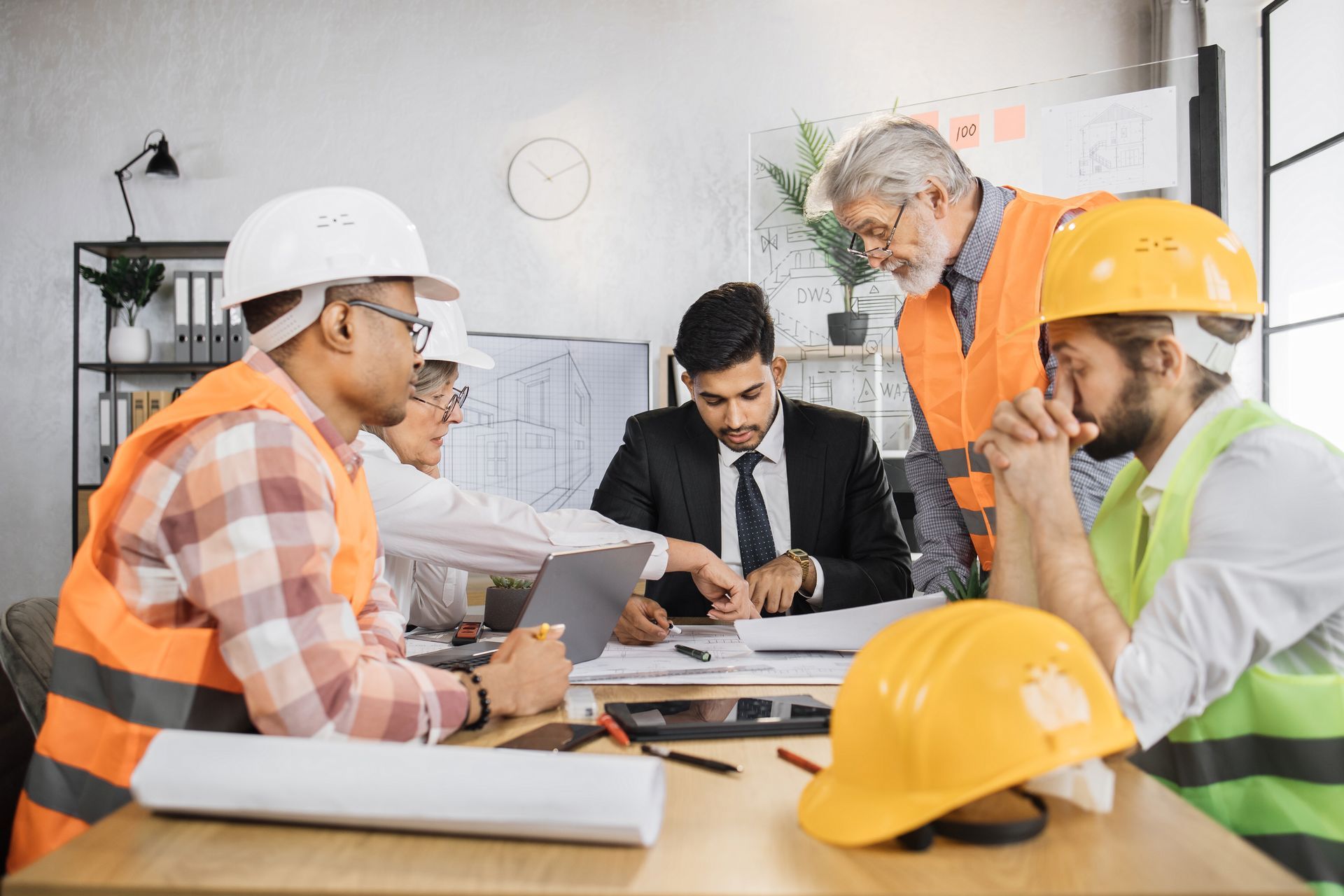 a group of construction workers are having a meeting in an office .