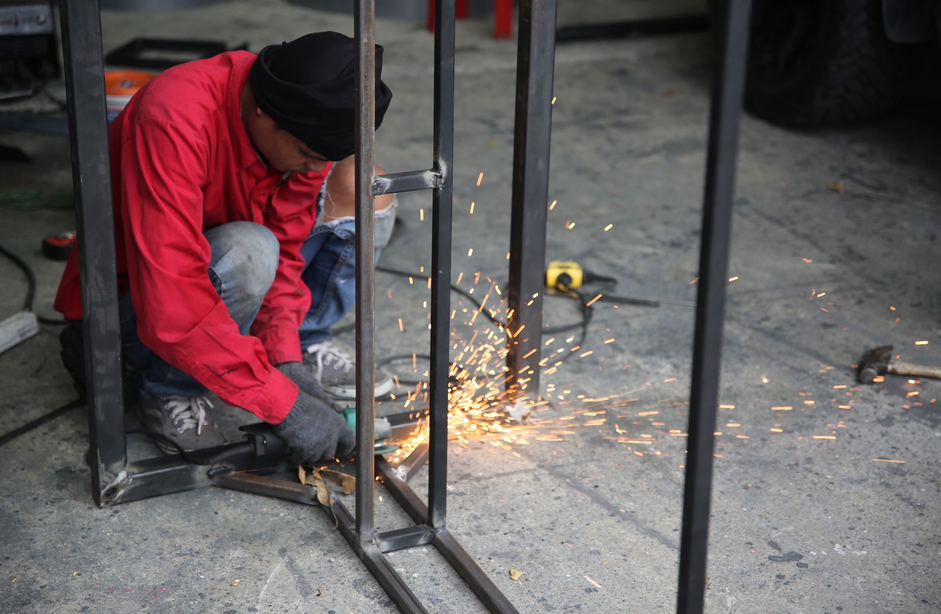 a man in a red jacket is grinding a piece of metal .
