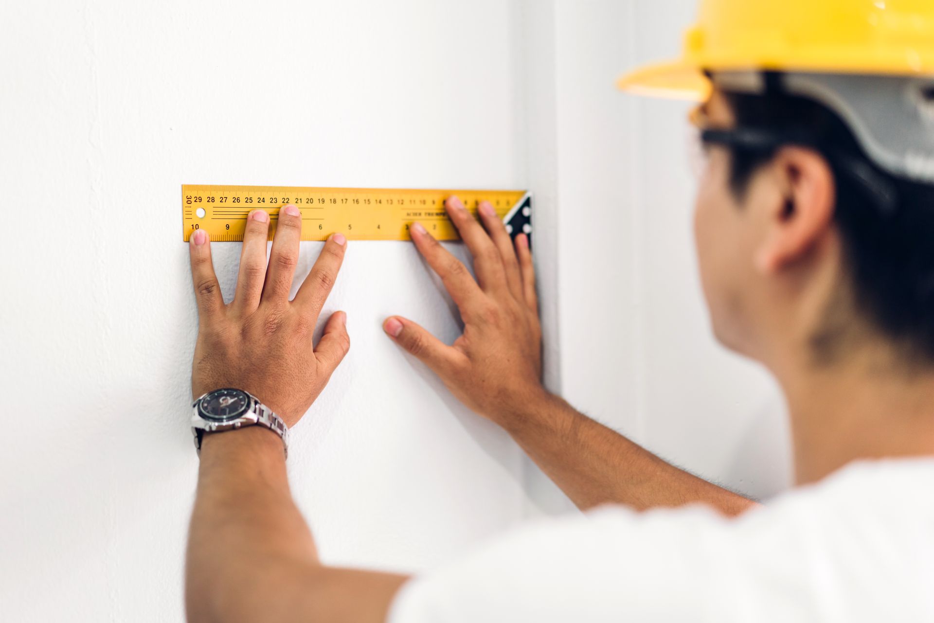 a man is measuring a wall with a ruler .
