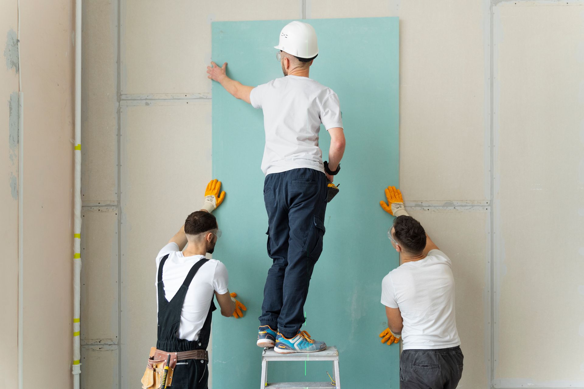 a group of construction workers are working on a wall .