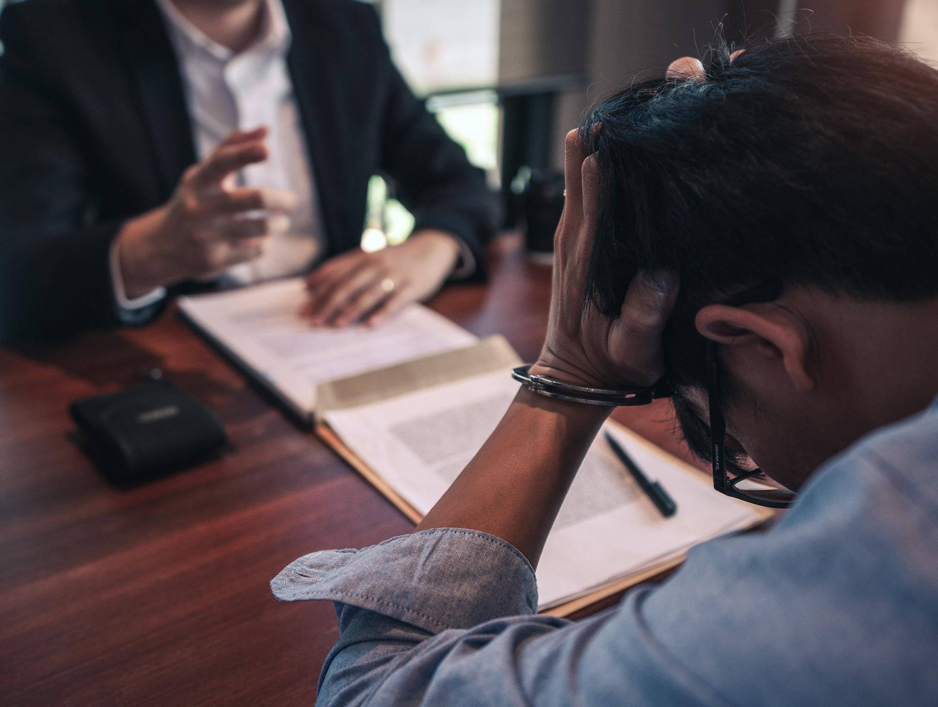 Counselor speaking with a stressed client at a desk, with papers and pen in a meeting room