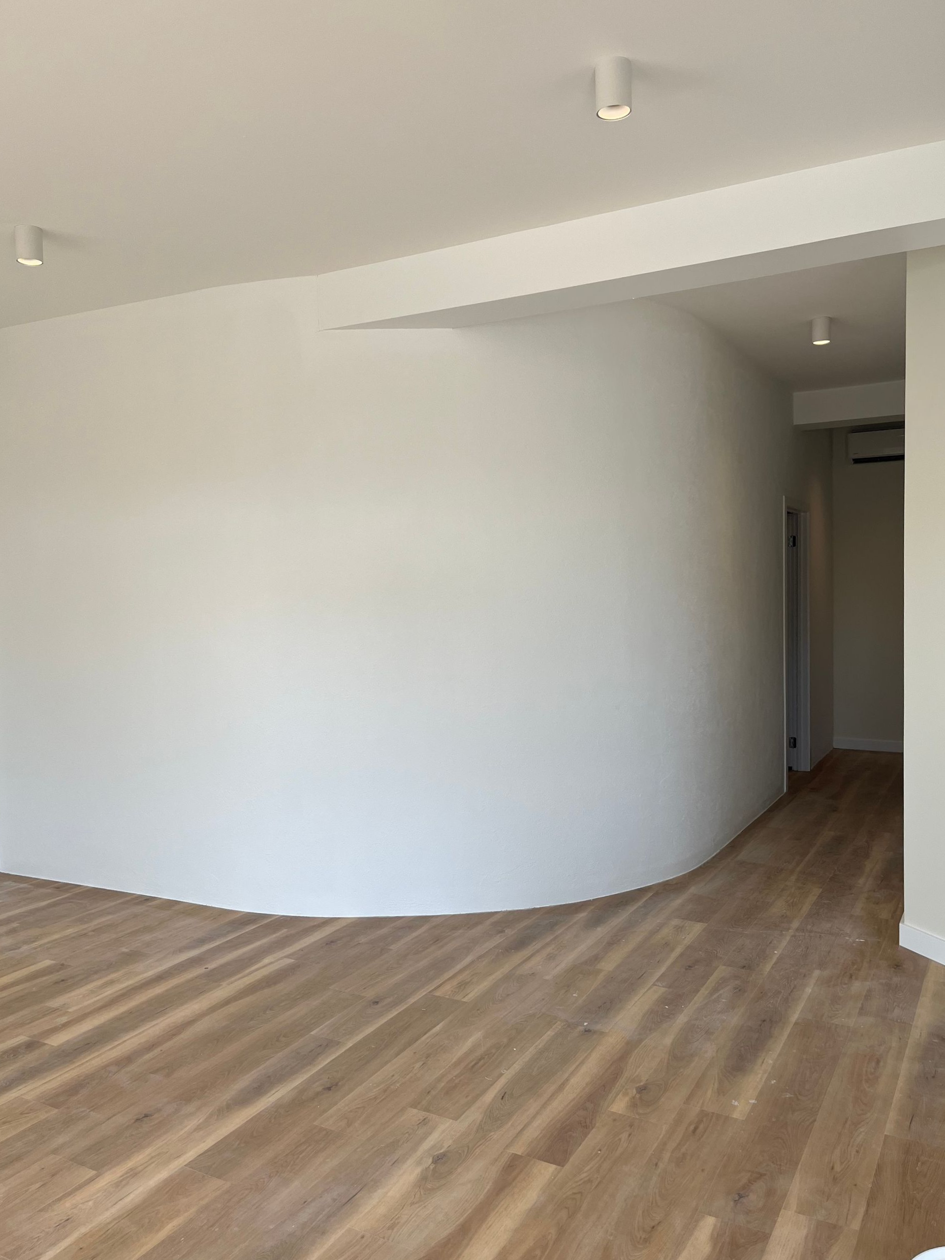 Empty room with curved white wall, wood floor, recessed lights — GV painting in Shepparton, VIC