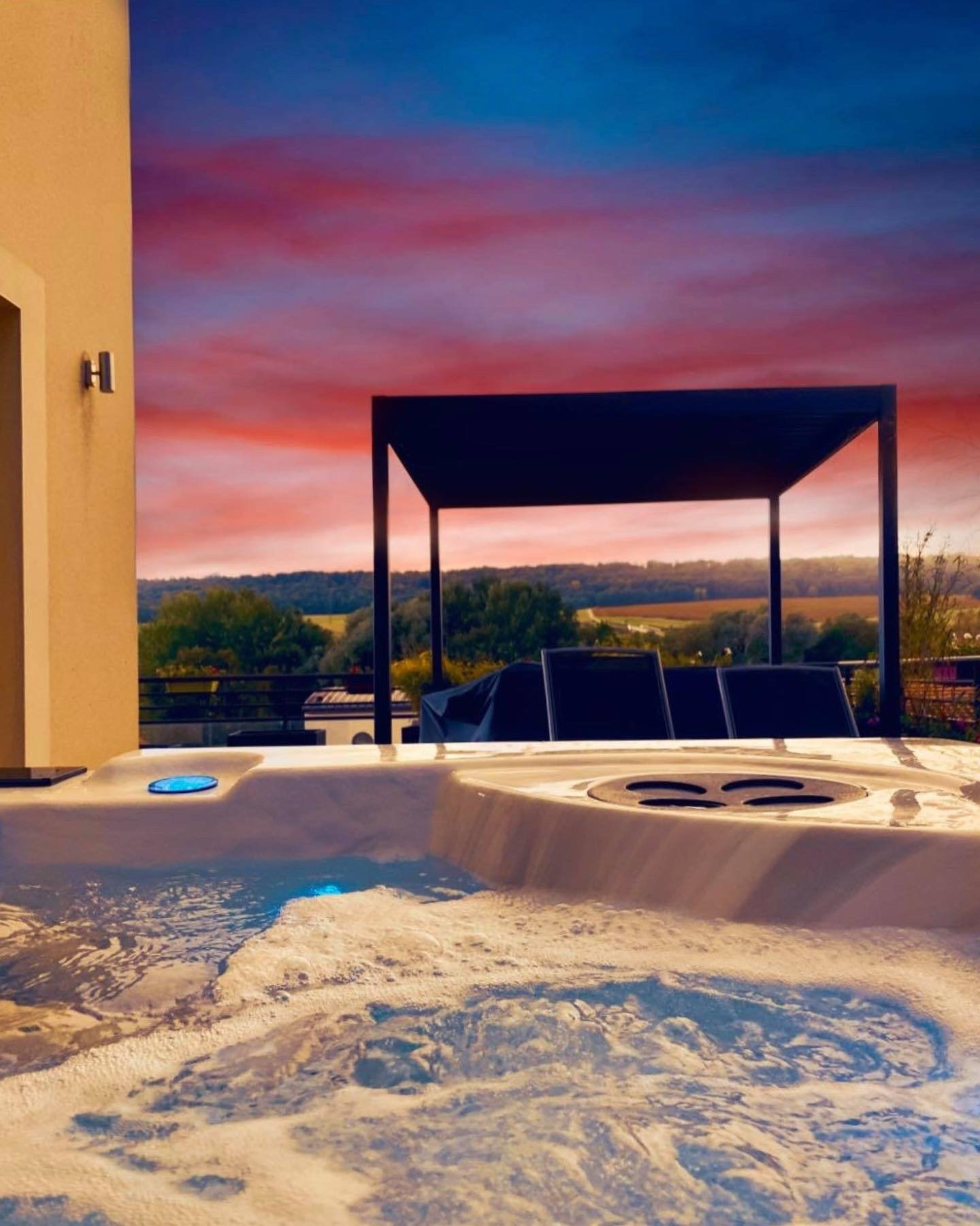 Un jacuzzi avec une pergola en arrière-plan au coucher du soleil