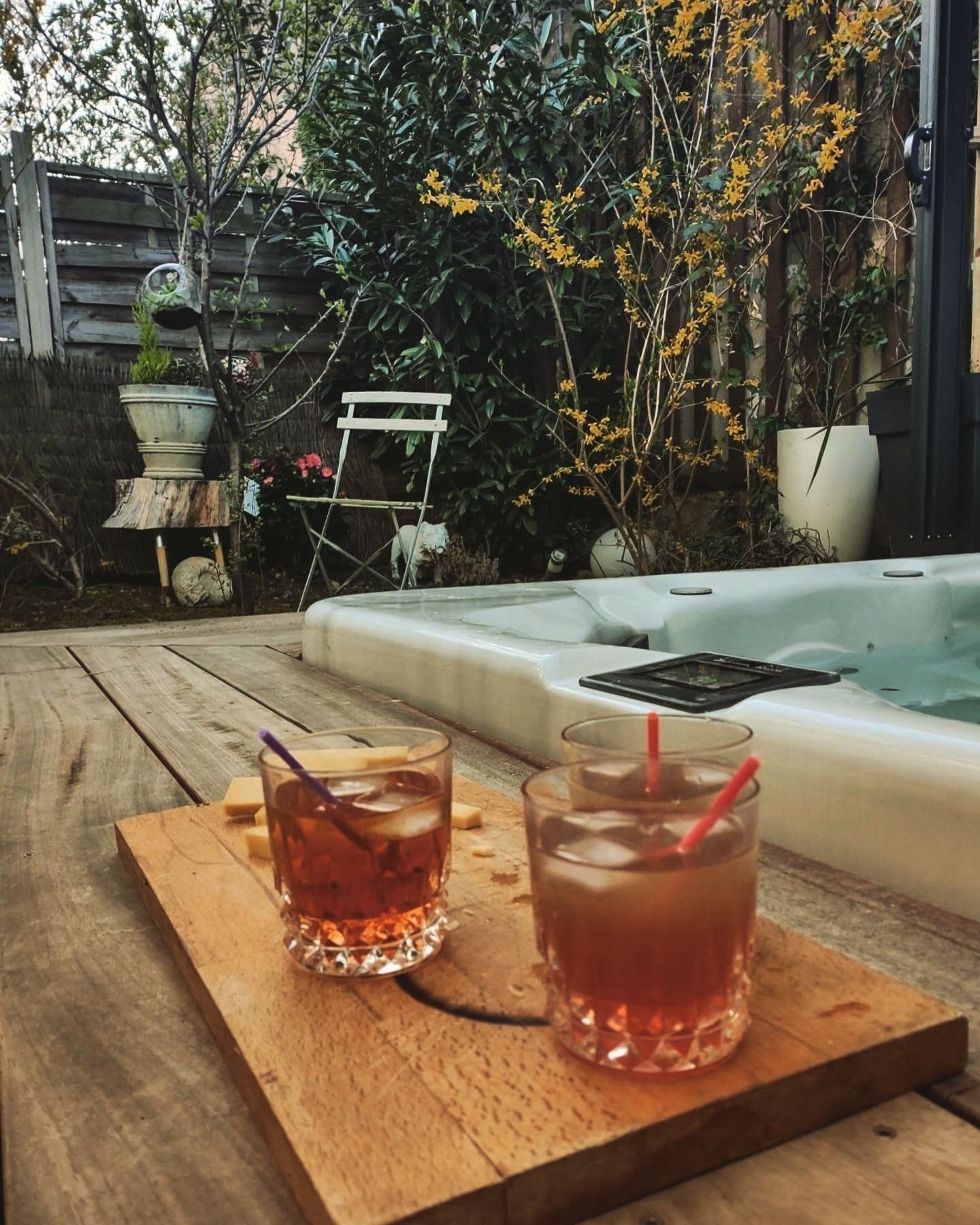Deux boissons sur une planche à découper en bois à côté d'un bain à remous.