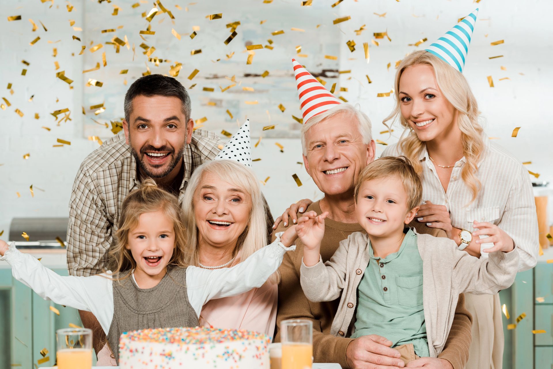 La famiglia festeggia con torta, cappellini da festa e coriandoli.