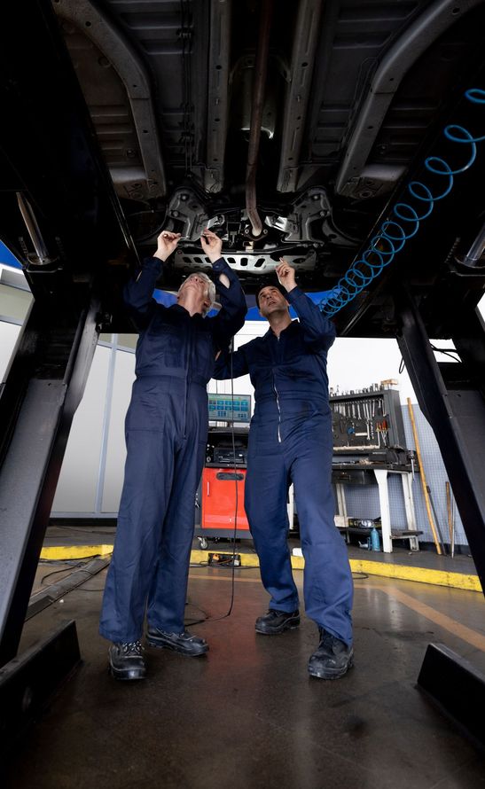 Two Man is Working Underneath a Car — Smyrna, GA — All Pro Transmission Exchange LLC Two Man is Working Underneath a Car — Smyrna, GA — All Pro Transmission Exchange LLC