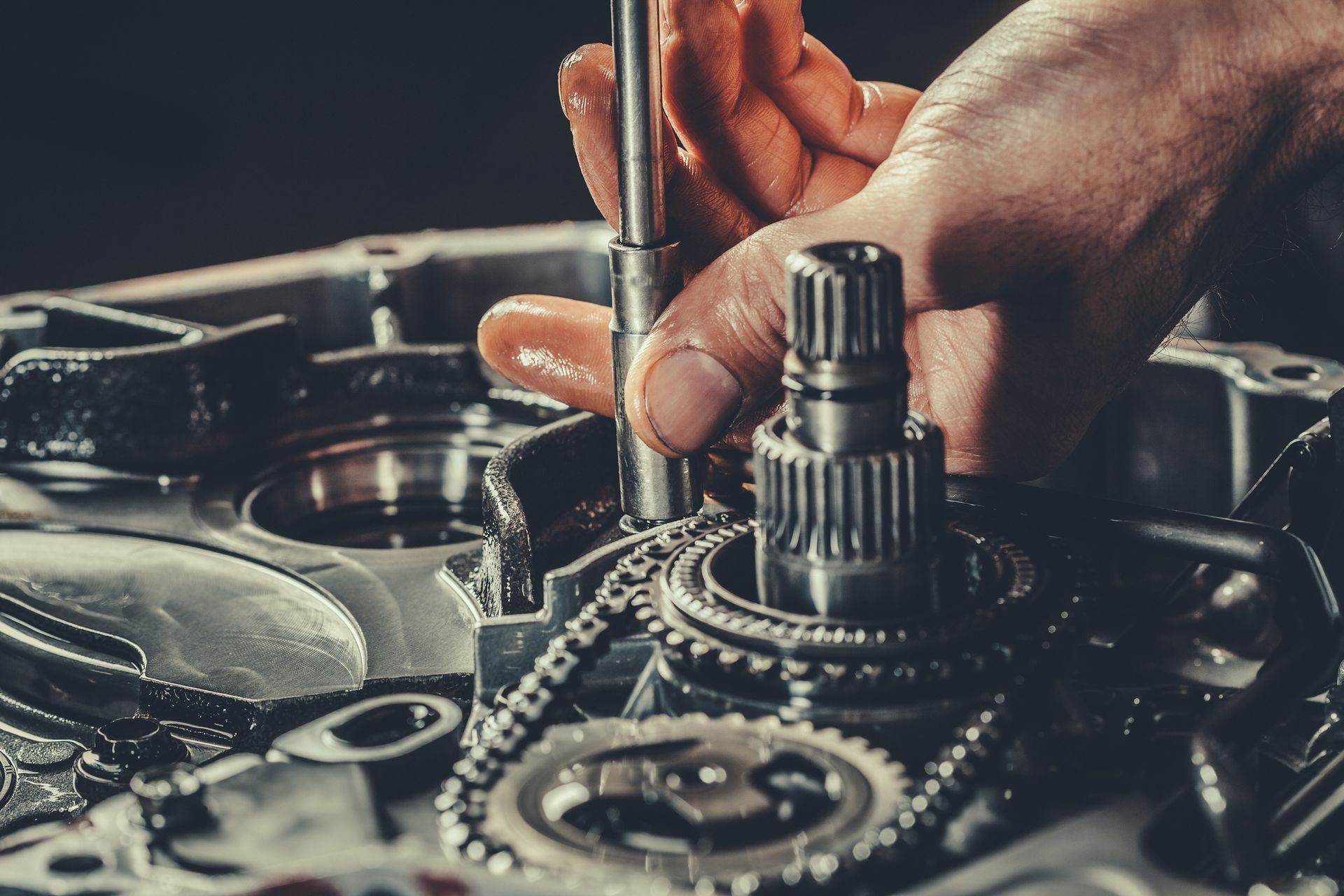 Close-up of a mechanic's hands performing auto transmission repair.